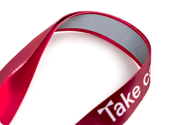 Close-up of a red rPET reflective lanyard with custom printing, featuring a sewn-on reflective stripe for night safety.